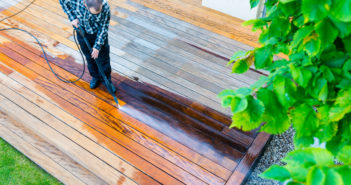 power washing - worker cleaning terrace with a power washer - high water pressure cleaner on wooden terrace surface
