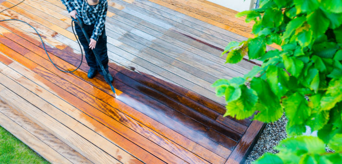 power washing - worker cleaning terrace with a power washer - high water pressure cleaner on wooden terrace surface